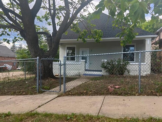 bungalow with roof with shingles, a fenced front yard, a gate, and stucco siding