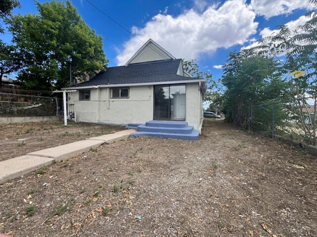 back of property featuring fence and stucco siding