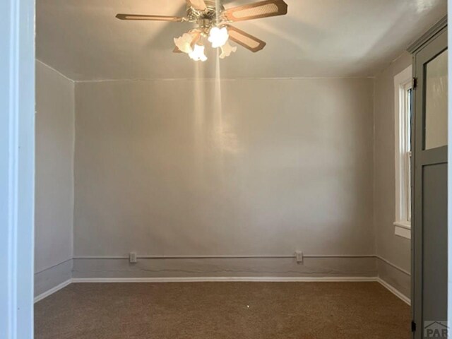 spare room featuring dark carpet, a ceiling fan, and baseboards