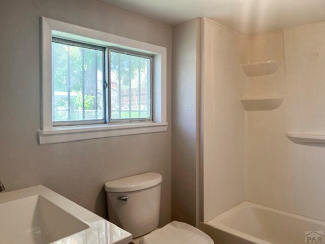 bathroom featuring toilet, tub / shower combination, and a sink