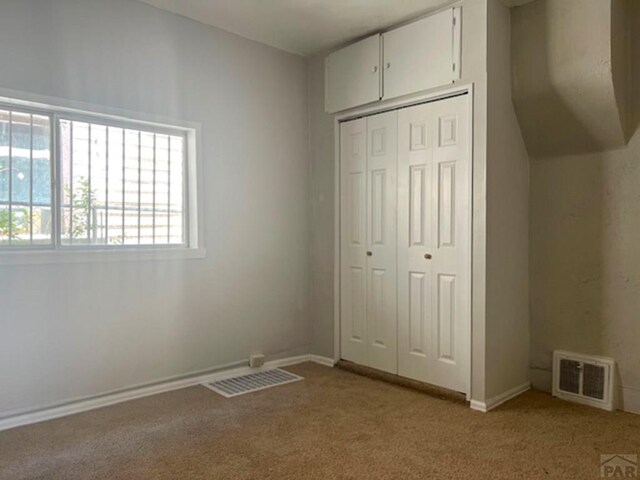 unfurnished bedroom with light carpet, a closet, visible vents, and baseboards