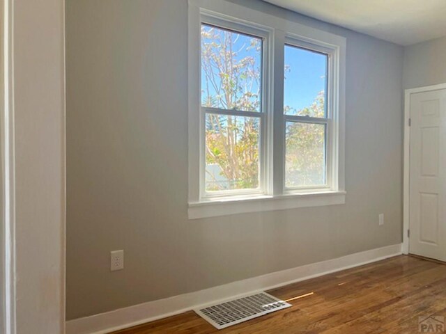 unfurnished room featuring baseboards, visible vents, and dark wood-type flooring