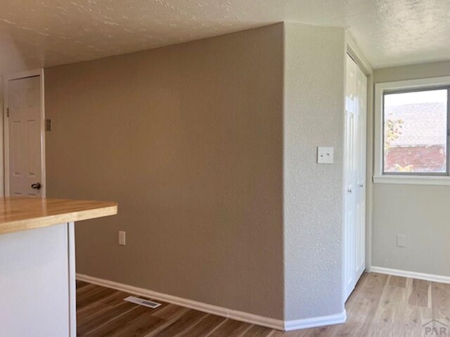 interior space featuring a textured ceiling, light countertops, wood finished floors, and baseboards