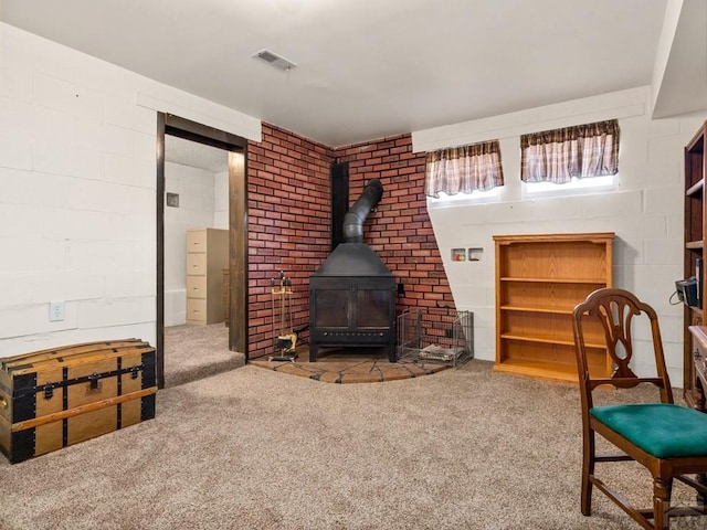 1040 28th Ln, Pueblo, CO 81006 - carpeted living area featuring a wood stove, visible vents, and concrete block wall