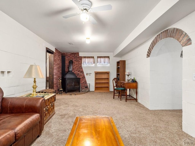 1040 28th Ln, Pueblo, CO 81006 - living room with a wood stove, ceiling fan, carpet flooring, and concrete block wall