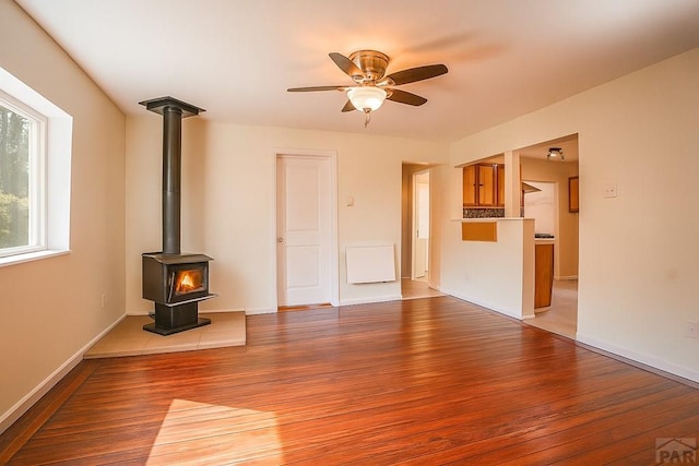 202 Pinon St, Walsenburg, CO 81089 - unfurnished living room featuring wood finished floors, a wood stove, and a ceiling fan