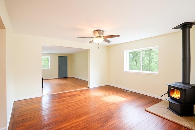 202 Pinon St, Walsenburg, CO 81089 - unfurnished living room featuring a wood stove, plenty of natural light, hardwood / wood-style flooring, and ceiling fan