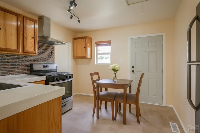 202 Pinon St, Walsenburg, CO 81089 - kitchen with stainless steel gas range oven, wall chimney range hood, light flooring, light countertops, and decorative backsplash