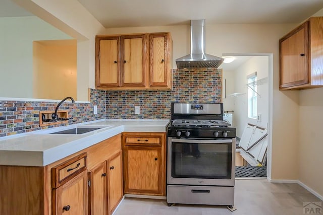 202 Pinon St, Walsenburg, CO 81089 - kitchen featuring stainless steel range with gas stovetop, wall chimney range hood, light countertops, brown cabinetry, and tasteful backsplash