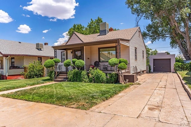 bungalow featuring a porch, concrete driveway, a front yard, a garage, and an outdoor structure