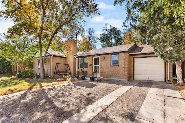 single story home with brick siding, a chimney, concrete driveway, entry steps, and a garage