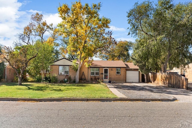 single story home featuring driveway, an attached garage, fence, a front yard, and brick siding