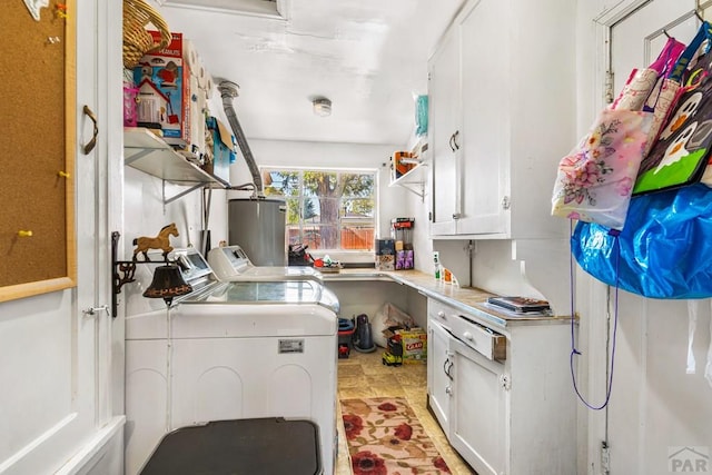 kitchen featuring water heater, light countertops, washing machine and dryer, and white cabinetry