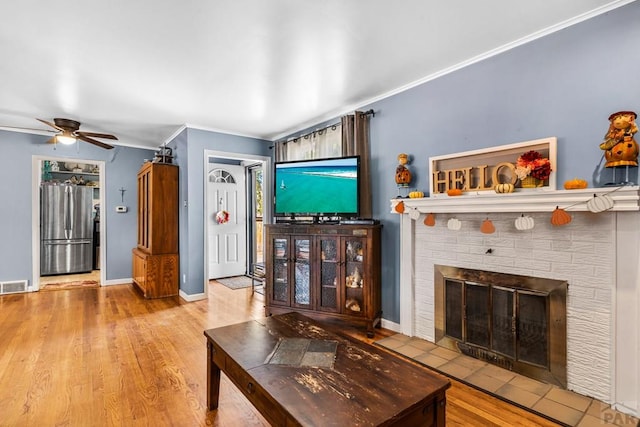 living room with ornamental molding, a fireplace, baseboards, and wood finished floors