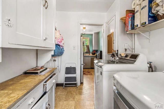 clothes washing area with washer and dryer and cabinet space