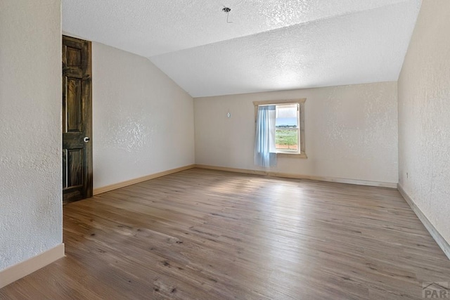 5010 Oak Grove Cir, Westcliffe, CO 81252 - empty room featuring lofted ceiling, a textured wall, light wood-style flooring, a textured ceiling, and baseboards