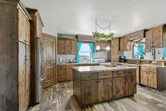 5010 Oak Grove Cir, Westcliffe, CO 81252 - kitchen with wood finished floors, a sink, light countertops, freestanding refrigerator, and a center island