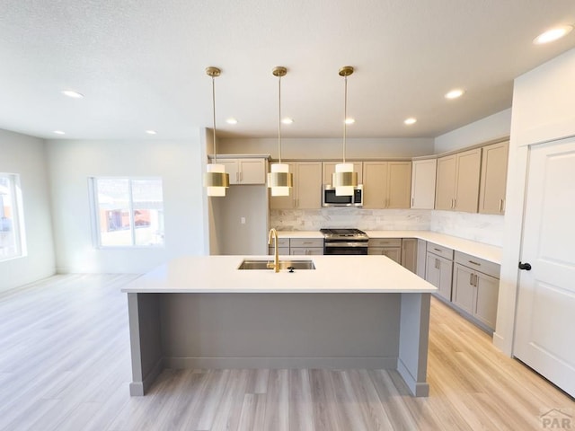 kitchen featuring tasteful backsplash, light wood-style flooring, stainless steel appliances, gray cabinetry, and a sink