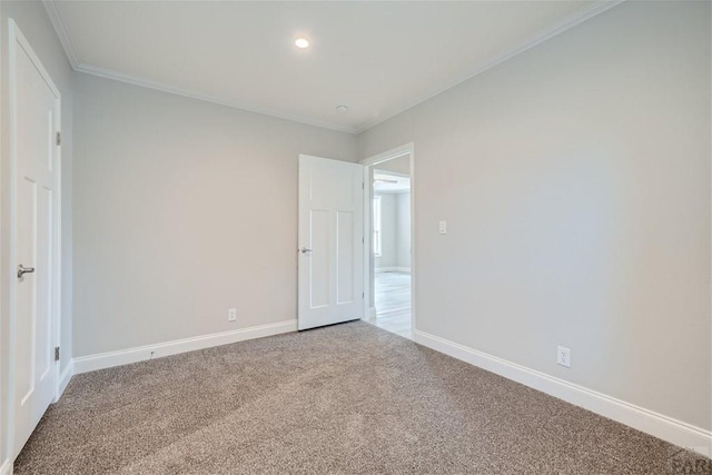 unfurnished room featuring carpet, crown molding, and baseboards