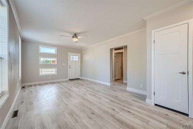 interior space featuring crown molding, baseboards, a ceiling fan, and light wood-style floors