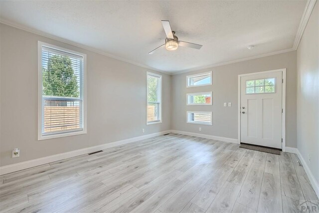 foyer entrance featuring visible vents, ornamental molding, light wood-style floors, ceiling fan, and baseboards