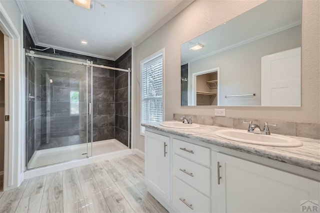 bathroom with a shower stall, a sink, and crown molding