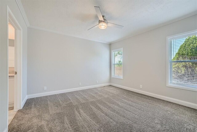 unfurnished room with a ceiling fan, light colored carpet, ornamental molding, and baseboards