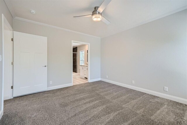 unfurnished bedroom with light carpet, baseboards, a ceiling fan, ensuite bath, and ornamental molding