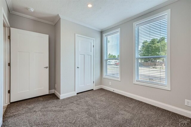 unfurnished bedroom with baseboards, a textured ceiling, carpet, and crown molding