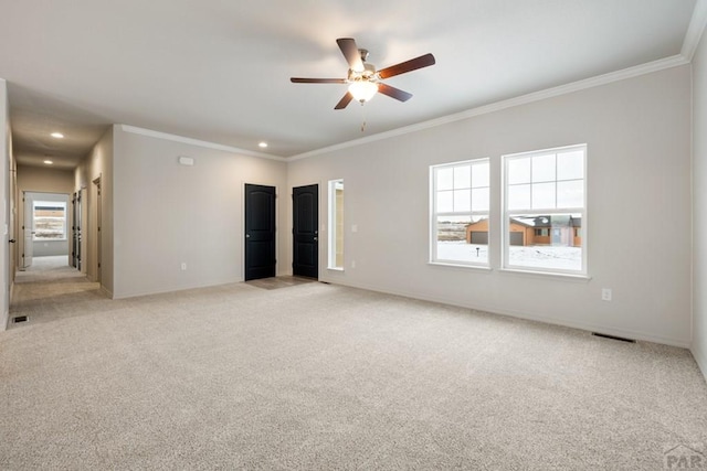 empty room featuring light carpet, crown molding, and baseboards