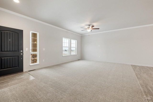interior space featuring light carpet, ceiling fan, baseboards, and crown molding