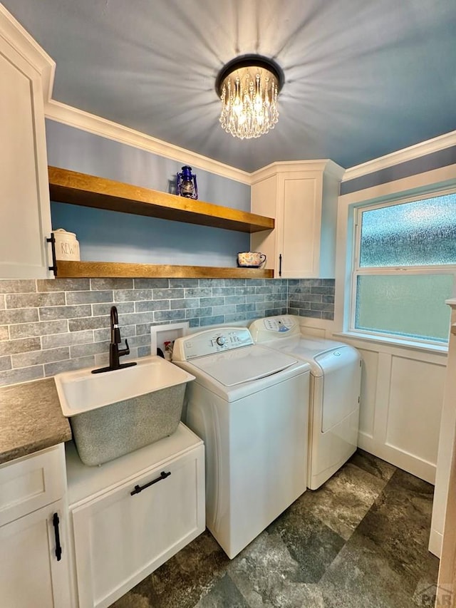 303 S Animas St, Trinidad, CO 81082 - laundry room with washing machine and clothes dryer, cabinet space, ornamental molding, dark stone finish flooring, and a chandelier