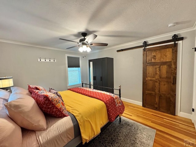 303 S Animas St, Trinidad, CO 81082 - bedroom with a barn door, wood finished floors, ornamental molding, ceiling fan, and a textured ceiling