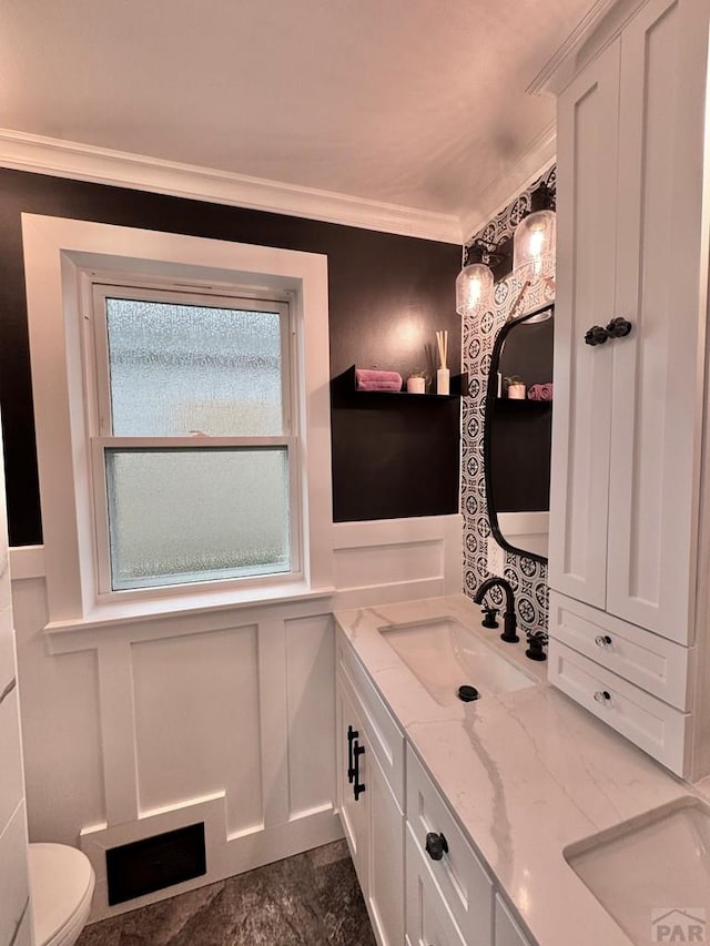 303 S Animas St, Trinidad, CO 81082 - bathroom featuring double vanity, crown molding, wainscoting, and a decorative wall