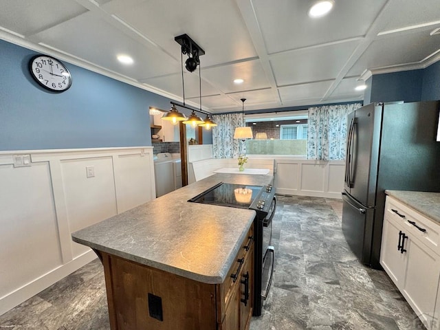 303 S Animas St, Trinidad, CO 81082 - kitchen with freestanding refrigerator, black range with electric cooktop, a kitchen island, a decorative wall, and washing machine and clothes dryer
