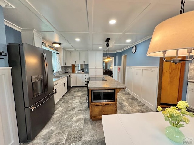 303 S Animas St, Trinidad, CO 81082 - kitchen with black fridge with ice dispenser, stainless steel microwave, dishwashing machine, recessed lighting, and a kitchen island