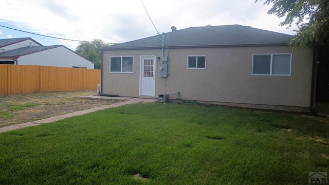 back of property with fence, a lawn, and stucco siding