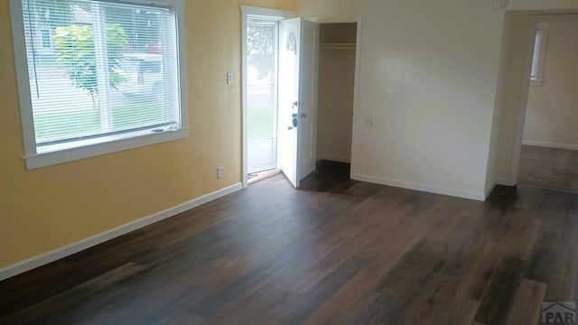 unfurnished room with dark wood-style floors and baseboards