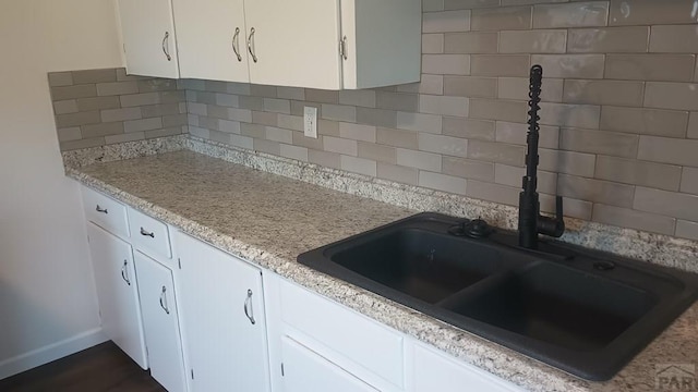 kitchen featuring tasteful backsplash, white cabinets, a sink, and light countertops