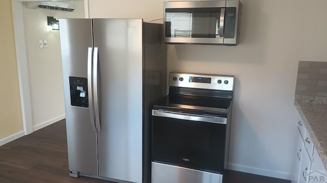 kitchen featuring baseboards, white cabinets, light stone counters, dark wood-type flooring, and stainless steel appliances