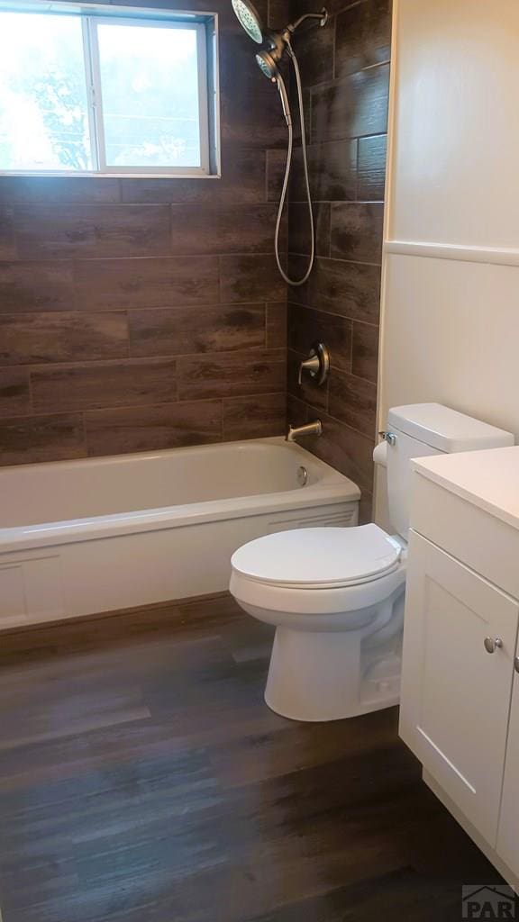 bathroom with toilet, bathing tub / shower combination, wood finished floors, and vanity