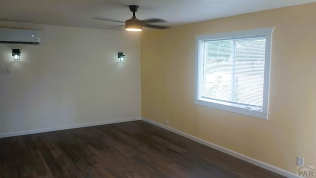 unfurnished room with a ceiling fan, an AC wall unit, baseboards, and dark wood-style floors