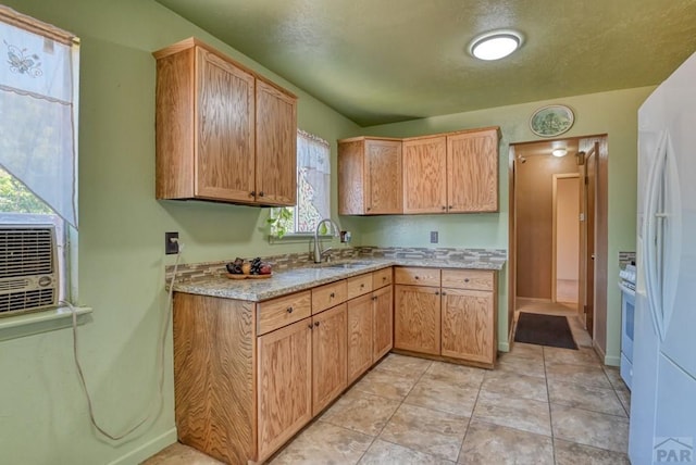 kitchen with baseboards, freestanding refrigerator, light stone countertops, a sink, and light tile patterned flooring