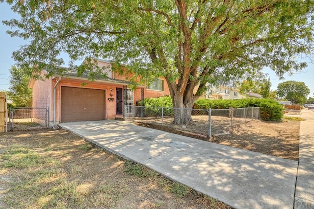 view of front of property featuring an attached garage, driveway, and a fenced front yard