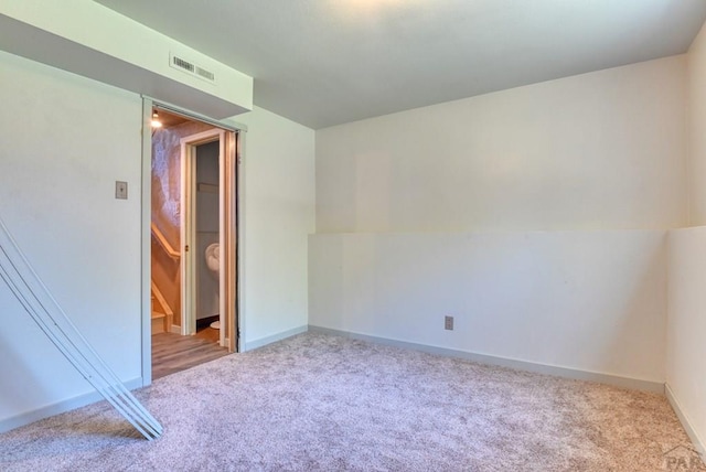 unfurnished room with visible vents, light carpet, and baseboards