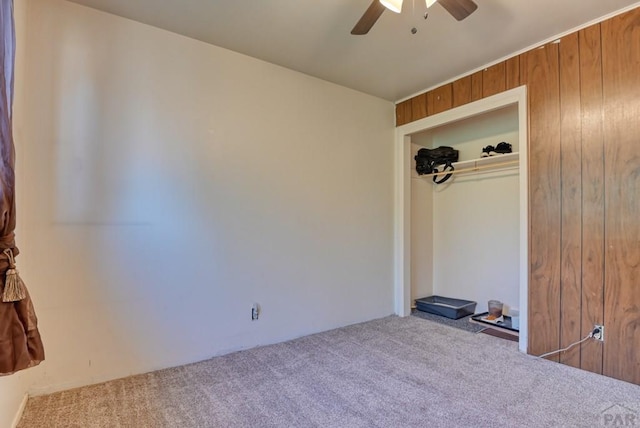 unfurnished room with light carpet, ceiling fan, and wooden walls