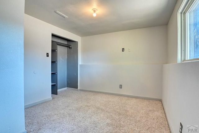 empty room featuring light carpet and baseboards