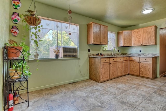 kitchen featuring baseboards, brown cabinets, and a sink