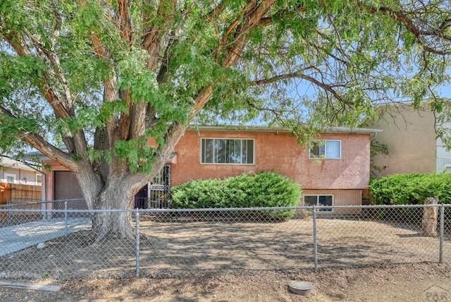 view of front of property featuring a garage, fence, and stucco siding