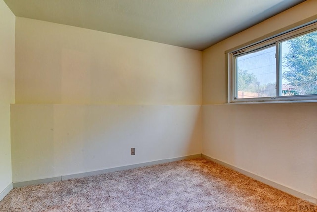 spare room featuring light carpet and baseboards